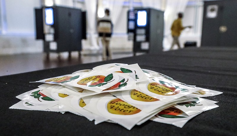 In this Tuesday, Aug. 11, 2020, file photo, stickers await voters on during the Georgia Primary in Atlanta. A federal judge has ordered Georgia to extend its deadline for accepting mail-in ballots for November's general election from the close of polls on Election Day until three days later. The secretary of state's office says it plans to immediately appeal the ruling. (John Spink/Atlanta Journal-Constitution via AP, File)