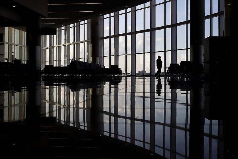 In this Monday, June 1, 2020 file photo, a woman looks through a window at a near-empty terminal at an airport in Atlanta. Anxiety and depression are rising among Americans compared with before the pandemic, research suggests. Half of those surveyed in a study released on Wednesday, Sept. 2, 2020, reported at least some signs of depression. (AP Photo/Charlie Riedel)