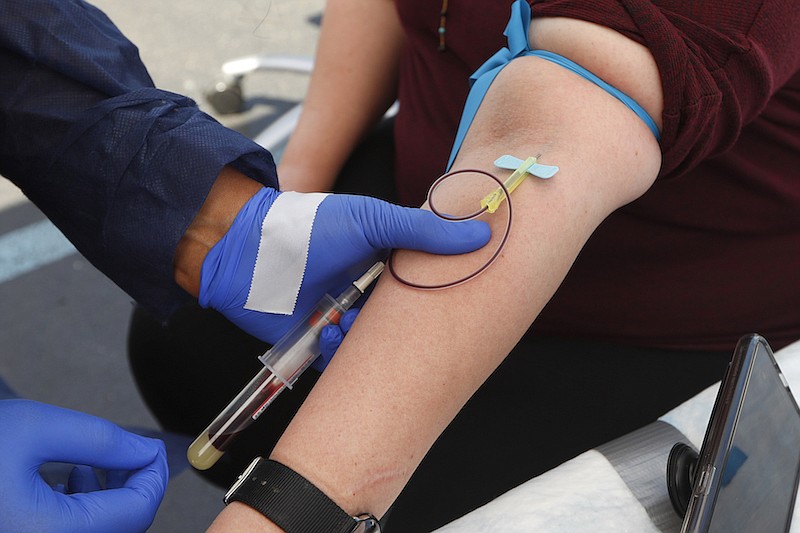 In this Friday, June 12, 2020 file photo, a woman has blood drawn for COVID-19 antibody testing in Dearborn, Mich. Antibodies that people make to fight coronavirus infection last at least four months and do not fade quickly as some earlier reports suggested -- a good sign that vaccines may be able to give long-lasting immunity, scientists are reporting on Tuesday, Sept. 1, 2020, in the New England Journal of Medicine. (AP Photo/Paul Sancya)