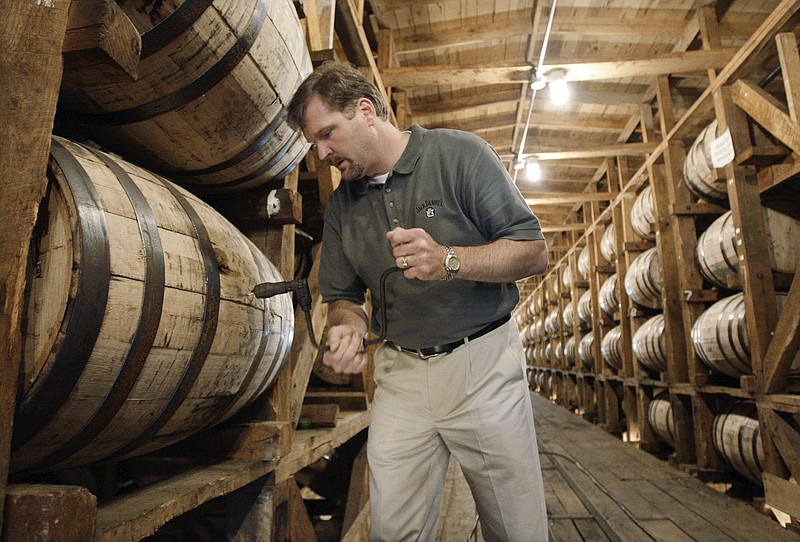 FILE — In this May 20, 2009, file photo, Jeff Arnett, the master distiller at the Jack Daniel Distillery in Lynchburg, Tenn., drills a hole in a barrel of whiskey in one of the aging houses at the distillery. After 12 years of leading production of the powerhouse Jack Daniel's whiskey brand, Arnett is stepping down as master distiller at the Tennessee distillery, the company announced Thursday, Sept. 3, 2020. (AP Photo/Mark Humphrey, File)