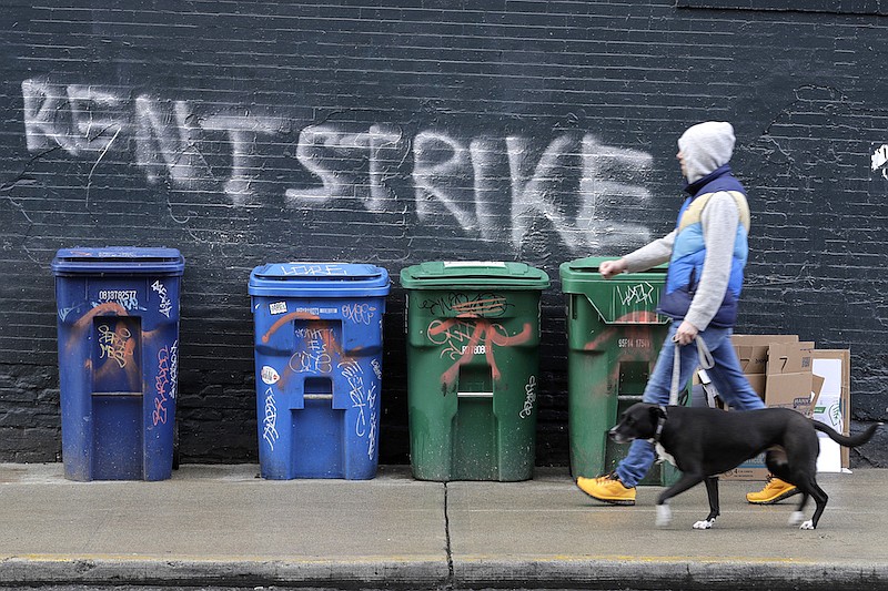 In this April 1, 2020, file photo, a pedestrian walks past graffiti that reads "Rent Strike" in Seattle's Capitol Hill neighborhood. The White House announced Tuesday, Sept. 1, that the Centers for Disease Control and Prevention would act under its broad powers to prevent the spread of the coronavirus. The measure would forbid landlords from evicting anyone for failure to pay rent, providing the renter meets criteria. (AP Photo/Ted S. Warren, File)