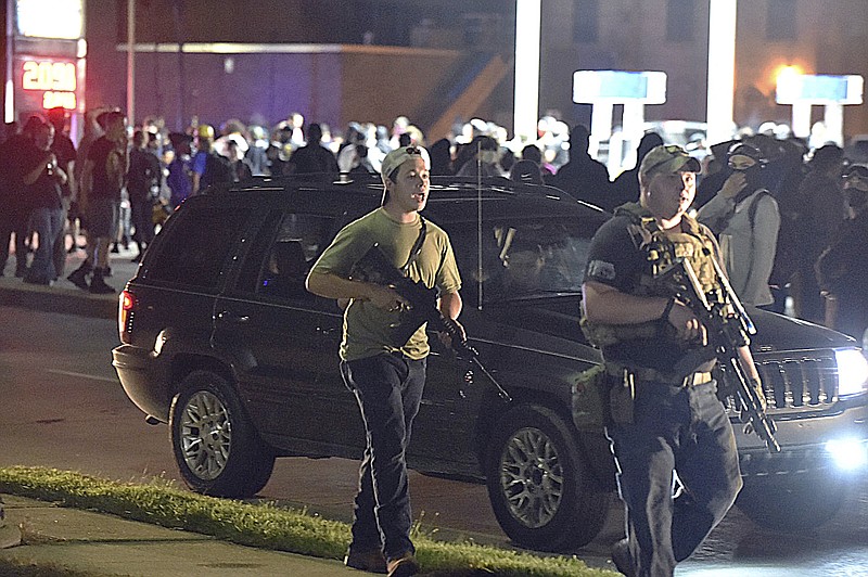 Photo by Adam Rogan/The Journal Times via The Associated Press / Kyle Rittenhouse, at left in backwards cap, walks along Sheridan Road in Kenosha, Wisconsin, at around 11 p.m. on Tuesday, Aug. 25, 2020, with another armed civilian Tuesday night. Less than an hour later Rittenhouse, a 17-year-old from Illinois, is accused of shooting three other people, killing two of them, with at least two of the shootings captured on video by onlookers showing Rittenhouse as the shooter.