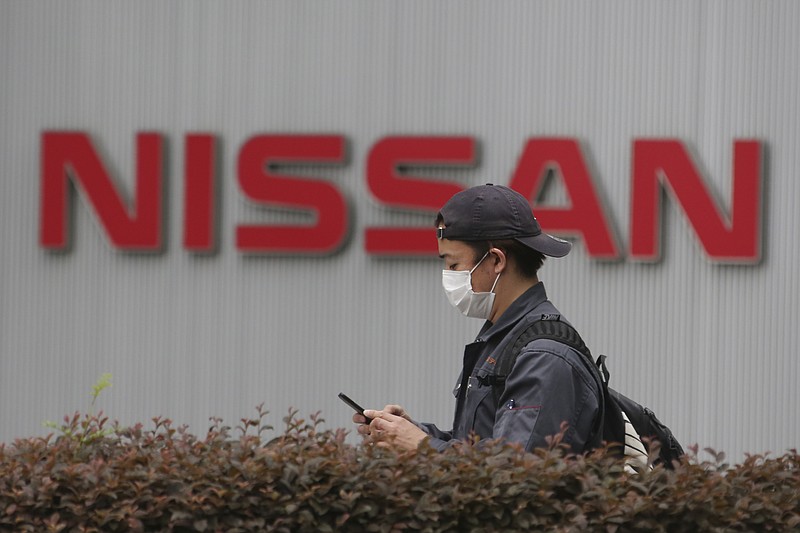 A man walks past the corporate logos at the global headquarters of Nissan Motor Co., Ltd. in Yokohama near Tokyo, Thursday, May 21, 2020. Nissan says it is developing a new way to produce auto parts, highlighting the Japanese automaker's engineering finesse, even as it struggles to recover from a scandal centered around its former chairman, Carlos Ghosn. (AP Photo/Koji Sasahara)