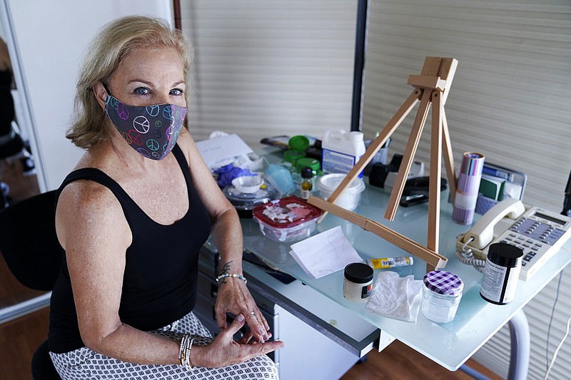 Artist Irene Pressner poses for a photograph on Aug. 21, 2020, in Aventura, Fla. The Venezuelan artist, a COVID-19 survivor who lost her husband to the virus, is creating new works inspired by her experience. (AP Photo/Lynne Sladky)