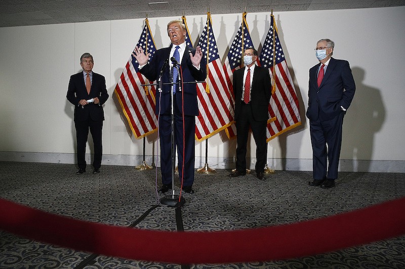 In this May 19, 2020, file photo President Donald Trump speaks with reporters after meeting with Senate Republicans at their weekly luncheon on Capitol Hill in Washington. Standing behind Trump are Sen. Roy Blunt, R-Mo., from left, Sen. John Barrasso, R-Wyo., and Senate Majority Leader Mitch McConnell of Ky. The battle for control of Congress this fall is solidifying into a race about Trump. (AP Photo/Patrick Semansky, File)