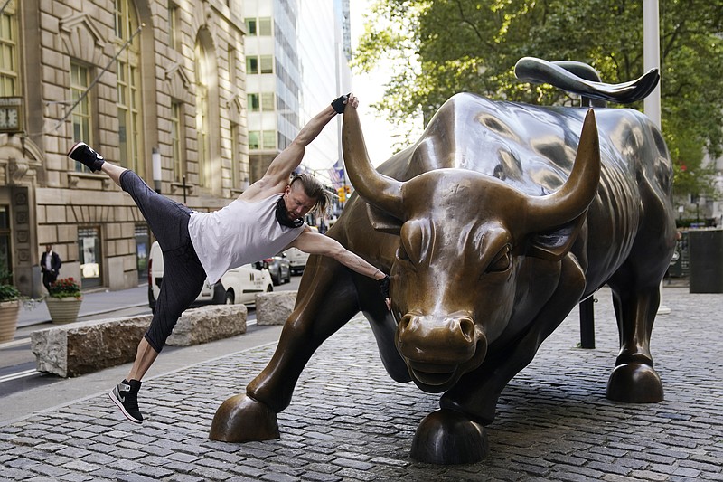 Stuart McKenzie, of London, takes a swing on the Charging Bull statue in New York's financial district, Tuesday, Sept. 8, 2020. More sharp declines for big tech stocks are dragging Wall Street toward a third straight loss on Tuesday. (AP Photo/Mark Lennihan)
