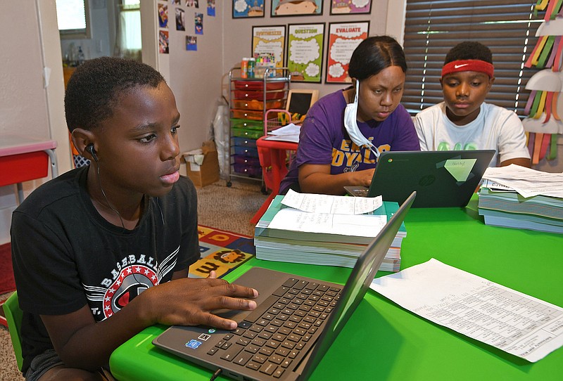 From left: Michael Henry, 11; his mother Mary Euell, 30; and his brother Mario Henry, 12, work through math lessons remotely at their west Erie, Pa., home, Tuesday, Sept. 8, 2020, on the first day of classes for the Erie School District. Most of the district's 11,000 students are beginning the school year with remote learning, to slow the spread of COVID-19, the new coronavirus. (Christopher Millette/Erie Times-News via AP)