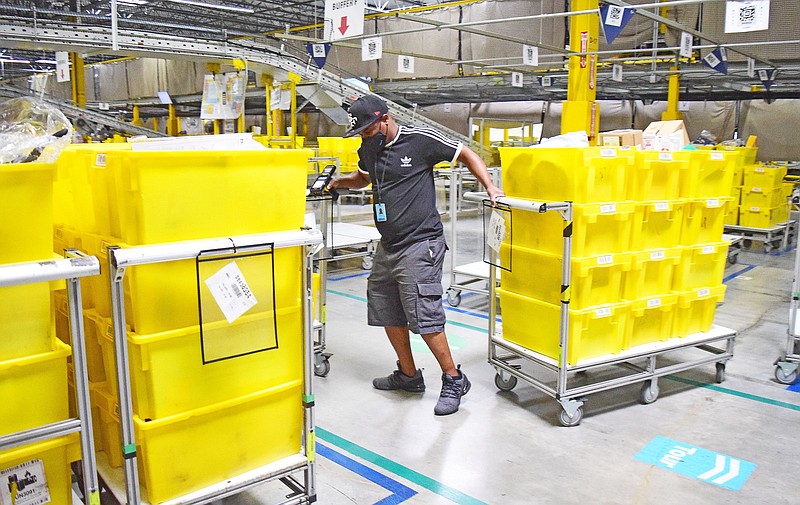 Staff File Photo by Robin Rudd / Amazon employee Oludare Bangbose moves cartons of merchandise in the company's huge facility at Enterprise South industrial park.