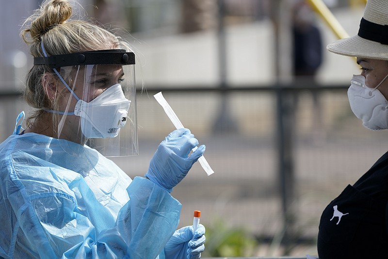 Associated Press File Photo / Nurse practitioner Debbi Hinderliter, left, collects a sample from a woman at a coronavirus testing site near San Diego.