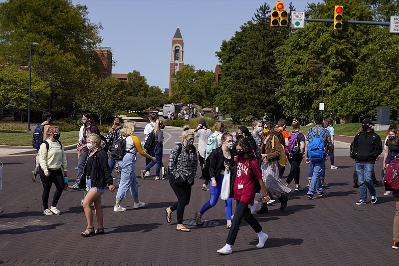 Masked students cross an intersection on the campus of Ball State University in Muncie, Ind., Thursday, Sept. 10, 2020. College towns across the U.S. have emerged as coronavirus hot spots in recent weeks as schools struggle to contain the virus. Out of nearly 600 students tested for the virus at Ball State, more than half have returned been found positive, according to data reported by the school. Dozens of infections have been blamed on off-campus parties, prompting university officials to admonish students. (AP Photo/Michael Conroy)