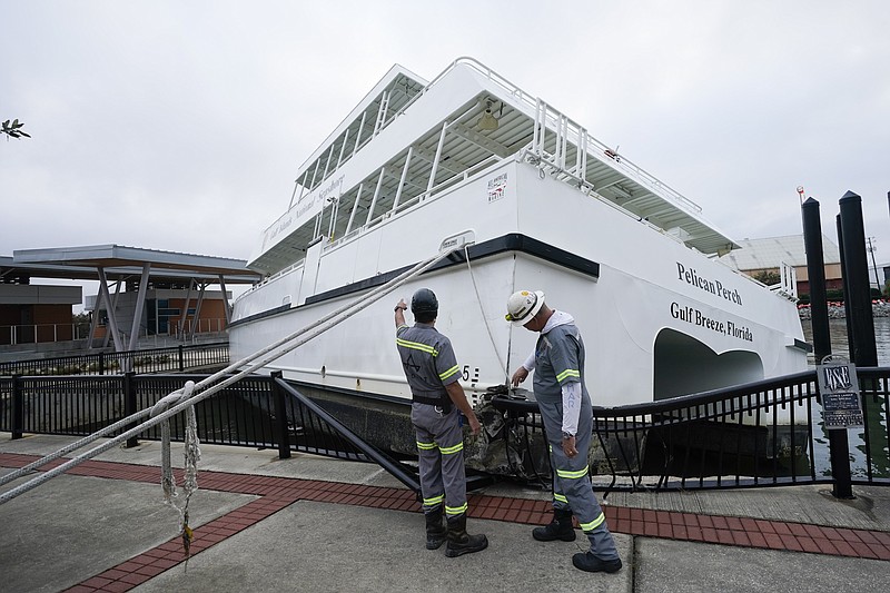 Workers look over a damaged ferry , Thursday, Sept. 17, 2020, in Pensacola, Fla. Rivers swollen by Hurricane Sally's rains threatened more misery for parts of the Florida Panhandle and south Alabama on Thursday, as the storm's remnants continued to dump heavy rains inland that spread the threat of flooding to Georgia and the Carolinas.(AP Photo/Gerald Herbert)