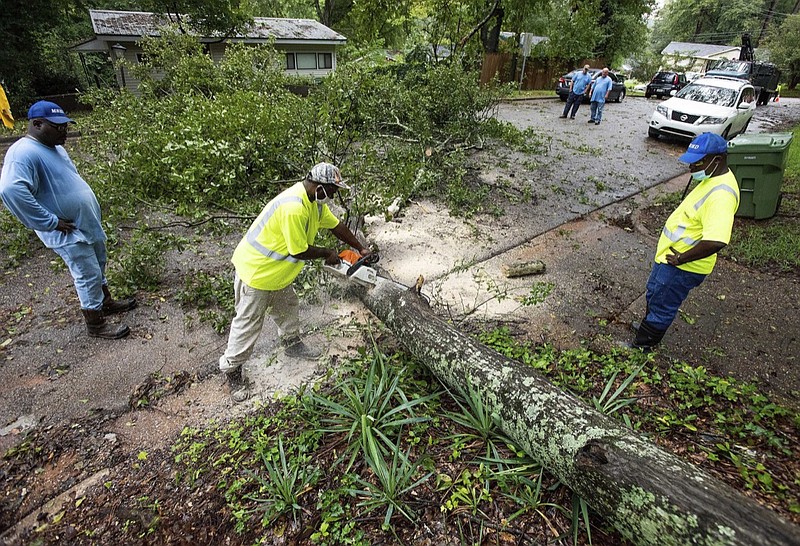 Crews cut up a large downed tree limb, Thursday, Sept. 17, 2020, in Montgomery, Ala. Homeowners and businesses along the soggy Gulf Coast have begun cleaning up in the wake of Hurricane Sally, even as the region braces for a delayed, second round of flooding in the coming days from rivers and creeks swollen by the storm's heavy rains. (Mickey Welsh/The Montgomery Advertiser via AP)