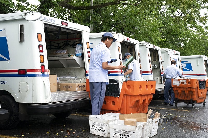 In this July 31, 2020, file photo, letter carriers load mail trucks for deliveries at a U.S. Postal Service facility in McLean, Va. A U.S. judge on Thursday, Sept. 17, 2020, blocked controversial Postal Service changes that have slowed mail nationwide. The judge called them "a politically motivated attack on the efficiency of the Postal Service" before the November election. (AP Photo/J. Scott Applewhite, File)