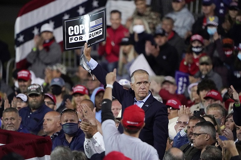 Sen. Tom Tillis, R-N.C. holds a sign as President Donald Trump speaks at a campaign rally, Saturday, Sept. 19, 2020 at the Fayetteville Regional Airport in Fayetteville, N.C. (AP Photo/Chris Carlson)
