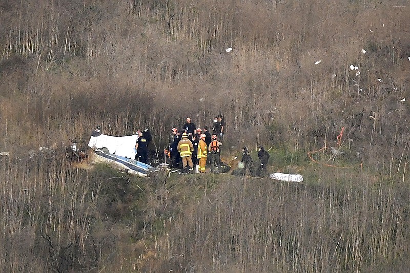 A body is covered, left, while another is seen at right at the scene of a helicopter crash that killed former NBA basketball player Kobe Bryant and eight others in Calabasas, Calif., Sunday, Jan. 26, 2020. Bryant's widow Vanessa Bryant on Tuesday, Sept. 22, 2020, filed a lawsuit against the Los Angeles County sheriff alleging negligence, invasion of privacy and intentional infliction of emotional distress after deputies allegedly shared unauthorized photos of the crash that killed her husband, their 13-year-old daughter and seven others. (AP Photo/Mark J. Terrill, File)