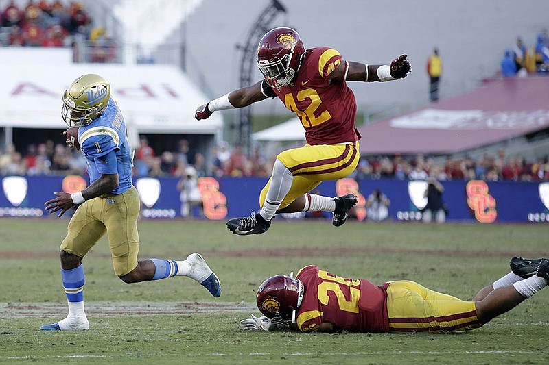 AP photo by Marcio Jose Sanchez / UCLA quarterback Dorian Thompson-Robinson, left, is chased by airborne Southern California linebacker Abdul-Malik McClain during the Pac-12 rivals' annual matchup in Los Angeles on Nov. 23, 2019.