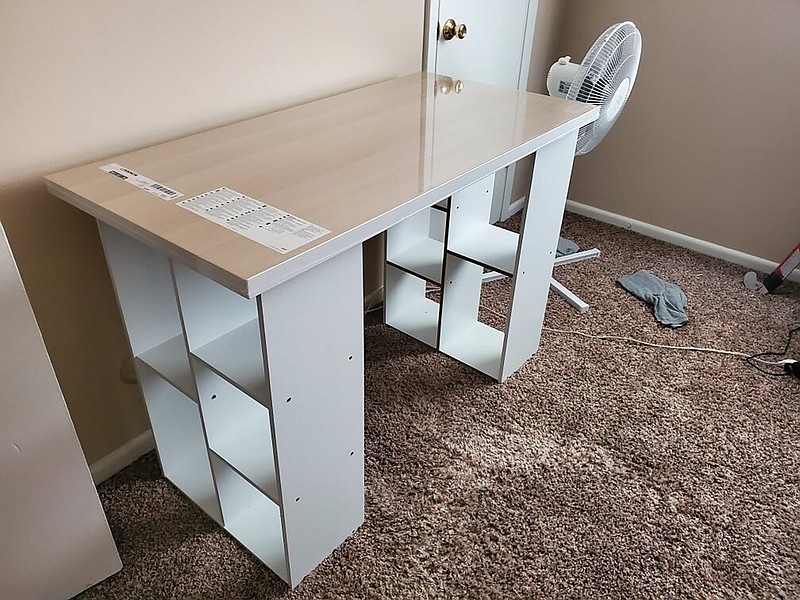 In this photo provided by Megan Fry, a desk Fry constructed out of a legless tabletop and bookcases stands in her Indianapolis home on Sept. 14, 2020. First it was toilet paper. Disinfectant wipes. Beans. Coins. Computers. Now, desks are in short supply because of the coronavirus pandemic. "It's not as cute or trendy as a bought desk and I wish it had drawers for storage," said Fry, who is starting a new work-from-home customer service job in Indianapolis in October. "But I'm happy it's clean and has a large surface on top for my monitors and laptop." (Megan Fry via AP)