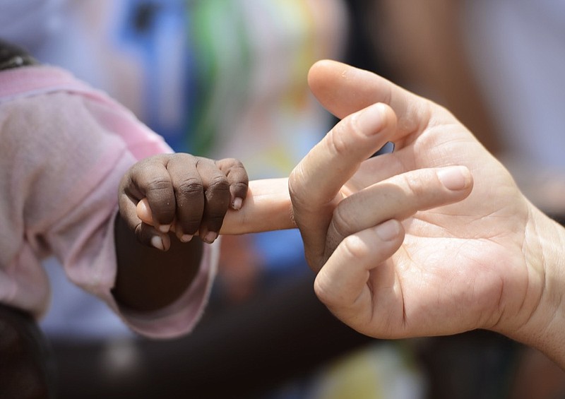 African Peace Symbol. White woman holds hands with a little baby native African girl, in Bamako, Mali. A black child and a white woman hold hands. Peace on earth symbol. Took this pic during my stay in Bamako, Mali in September 2015. A beautiful shot with lots of possible background symbols. No to Racism! / Getty Images
