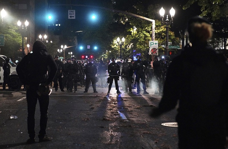 Portland Police line up blocking the street while protesters rally in front of them at the Mark O. Hatfield United States Courthouse on Saturday, Sept. 26, 2020, in Portland, Ore. (AP Photo/Allison Dinner)