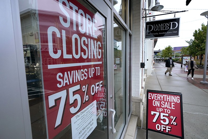 FILE - In this Sept. 2, 2020 file photo, pedestrians walk past a business storefront with store closing and sale signs in Dedham, Mass.  The U.S. economy plunged at a record rate in the spring but is poised to break a record for an increase in the just-ending July-September quarter. The Commerce Department reported Wednesday, Sept. 30, that the gross domestic product, the economy’s total output of goods and services, fell at a rate of 31.4% in the April-June quarter, only slightly changed from the 31.7% drop estimated one month ago.  (AP Photo/Steven Senne)