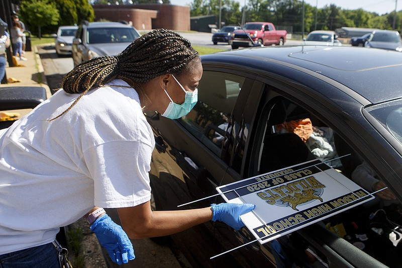 Staff photo by C.B. Schmelter / Emetria Arnold, the school social worker, passes out graduation yard signs at Hixson High School on Thursday, May 7, 2020, in Hixson, Tenn. The school had a graduation rate last year of 83.5%.