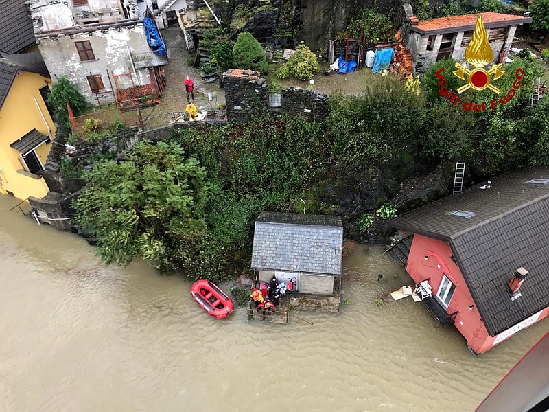 In this image made available Sunday, Oct. 4, 2020, firefighters evacuate people from a house amidst flooding in the town of Ornavasso, in the northern Italian region of Piedmont. (Firefighter Vigili del Fuoco via AP)