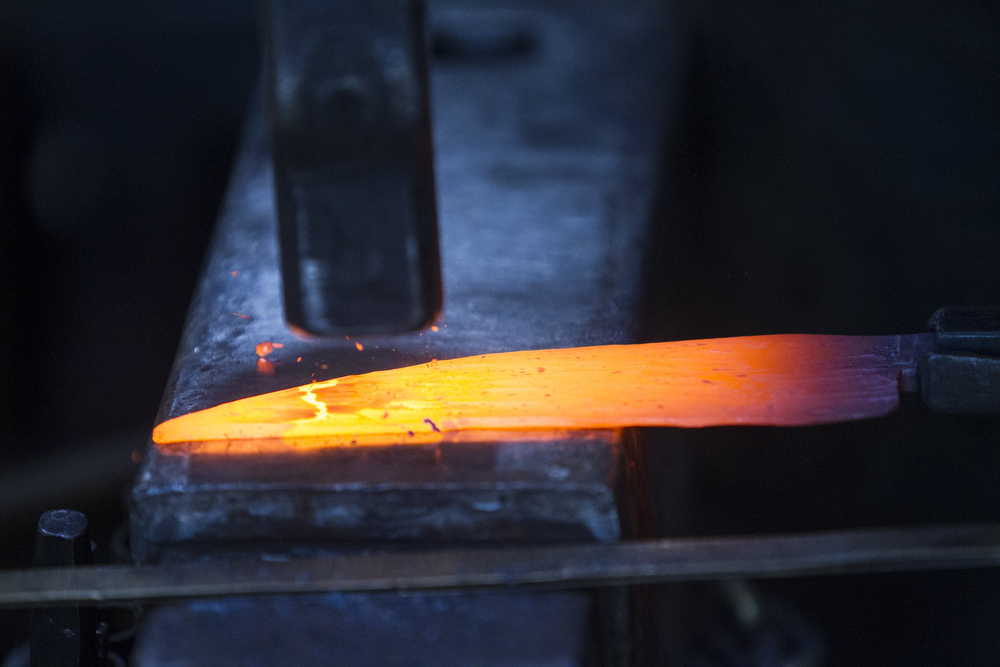 Staff photo by Troy Stolt / Mak Kelsay, owner and operator of 6Ear Knife and Tool hammers a red hot piece of steel into the shape of a kitchen knife inside of Kelsay's home, where he has a shop in his garage on Friday, Oct. 2, 2020 in Ooltewah, Tenn.