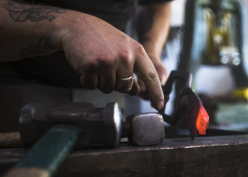 Staff photo by Troy Stolt / Mak Kelsay works with a red hot piece of steel to create a tang for a kitchen knife inside of Kelsay's home, where he has a shop in his garage on Friday, Oct. 2, 2020 in Ooltewah, Tenn.