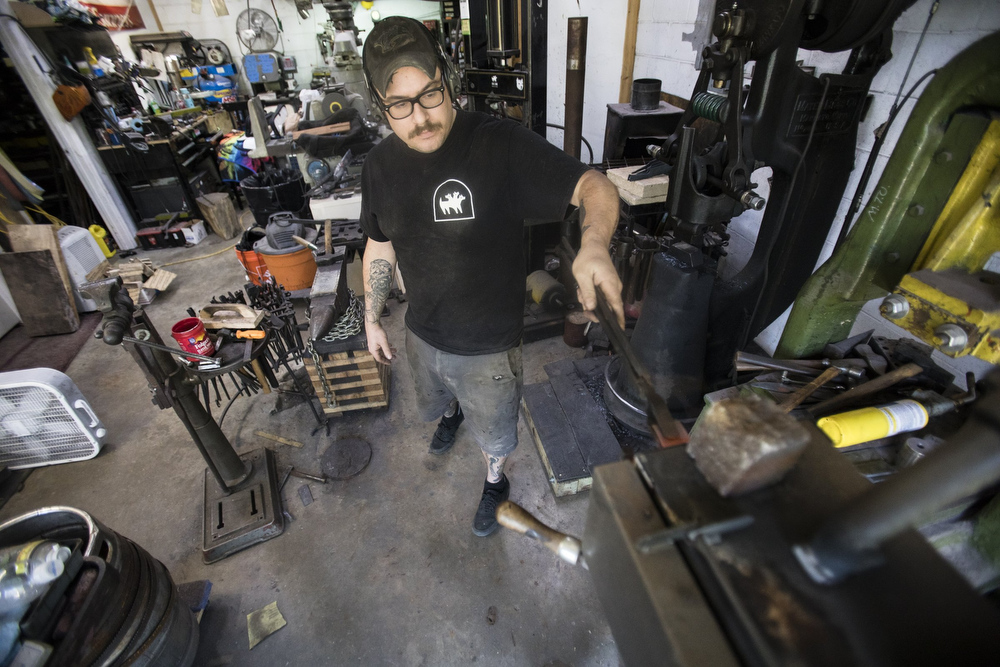 Staff photo by Troy Stolt / Mak Kelsay, owner and operator of 6ear Knife and Tool, pulls a piece of steel out of the forge inside of Kelsay's home, where he has a shop in his garage on Friday, Oct. 2, 2020 in Ooltewah, Tenn.