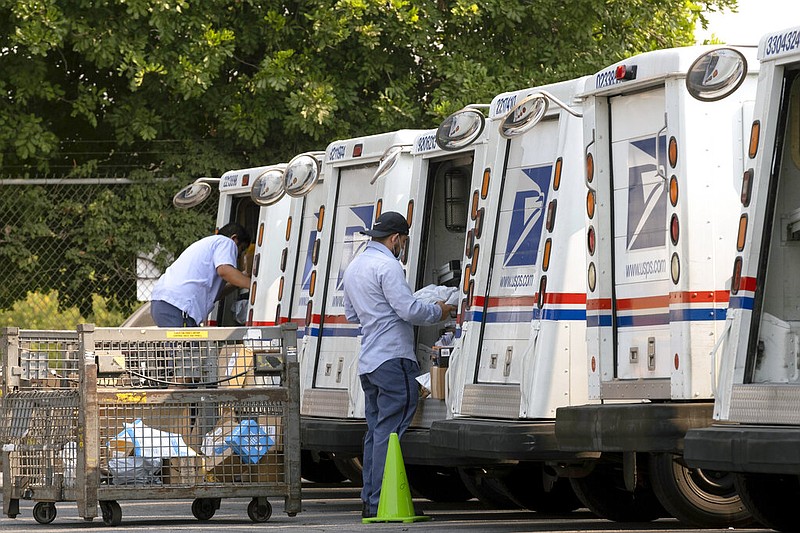 In this Aug. 20, 2020 file photo, postal workers load their mail delivery vehicles at the Panorama city post office in Los Angeles. The Nov. 3 election will test California's commitment to voting by mail as the nation's most populous state will offer fewer in-person polling places hoping it will convince more people to cast ballots from the safety of their mailboxes during a pandemic. If it doesn't work, the state could see long lines and frustrated voters on Election Day compounded by coronavirus protocols that will make voting in person slower in a year expected to draw a big turnout. (AP Photo/Richard Vogel, File)