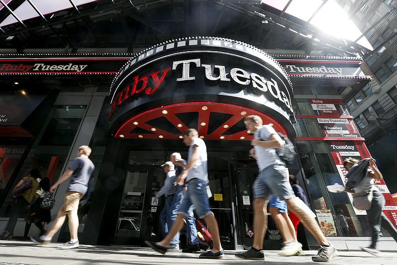 FILE - In this Sept. 16, 2016 file photo, visitors to New York's Times square walk past a Ruby Tuesday restaurant. Ruby Tuesday is filing for bankruptcy protection, the latest casual chain to suffer from coronavirus-related closures and changing consumer habits. The Maryville, Tennessee-based company says, Wednesday, Oct. 7, 2020 its restaurants will remain open throughout the bankruptcy process. (AP Photo/Mary Altaffer, File)