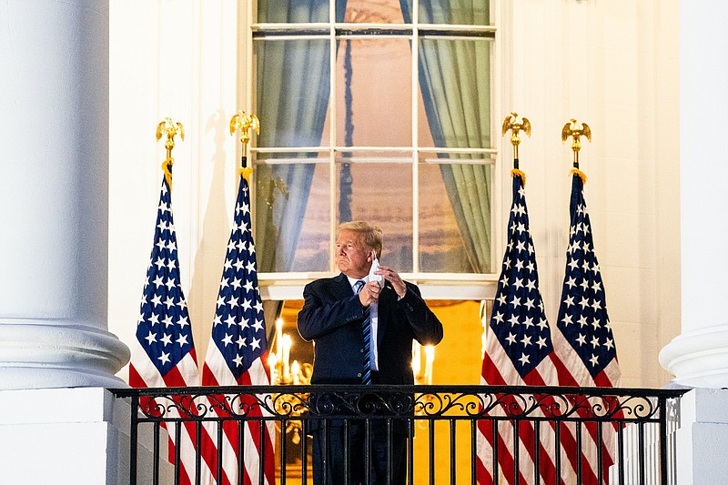 President Donald Trump removes his mask as he stands on the Truman Balcony upon returning to the White House Monday after testing positive for COVID-19 and spending four days at the the Walter Reed Medical Center in Bethesda, Maryland. / Photo by Anna Moneymaker/ New York Times