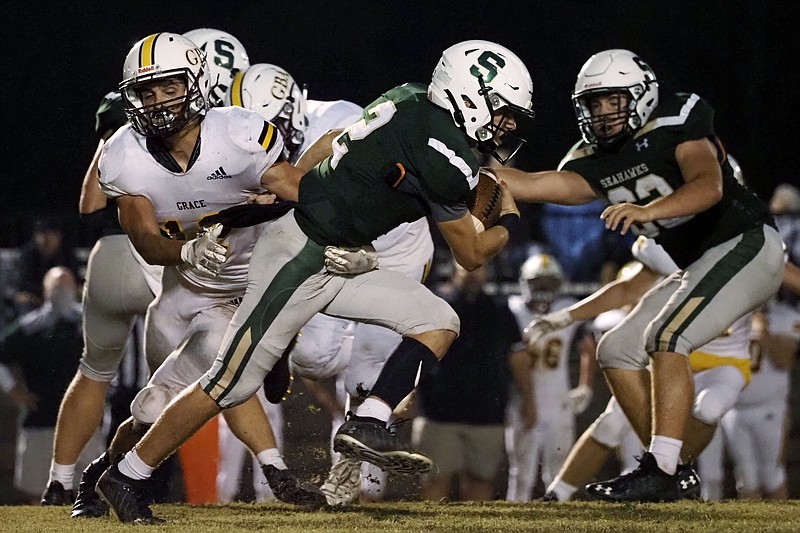 Staff photo by C.B. Schmelter / Silverdale Baptist Academy's Turner Junkins, center, gets away from Grace's Joseph Colbaugh, left, on Friday night. Junkins helped lead the host Seahawks to a 31-14 win as they improved to 4-3.