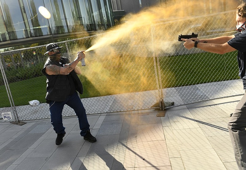 A man sprays mace, left, as another man fatally fires a gun, Saturday, Oct. 10, 2020 in Denver. The man on the left side of the photo was supporting the "Patriot Rally" and sprayed mace at the man on the right side of the image. The man at right, then shot and killed the protester at left. A private security guard working for a TV station was in custody Saturday after a person died from a shooting that took place during dueling protests in downtown Denver, the Denver Post reported. (Helen H. Richardson/The Denver Post via AP)