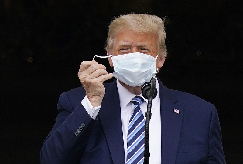 Photo by Alex Brandon of The Associated Press / President Donald Trump removes his face mask to speak from the Blue Room Balcony of the White House to a crowd of supporters on Saturday, Oct. 10, 2020, in Washington.