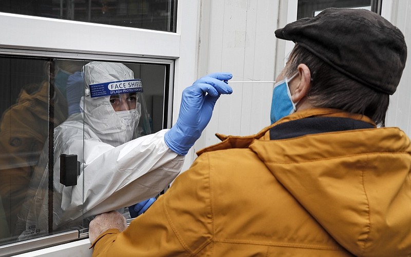 Medical staff takes a COVID-19 test at a coronavirus test center in Cologne, Germany, Thursday, Oct. 15, 2020. The city exceeded the important warning level of 50 new infections per 100,000 inhabitants in seven days. More and more German cities become official high risk corona hotspots with travel restrictions within Germany. (AP Photo/Martin Meissner)