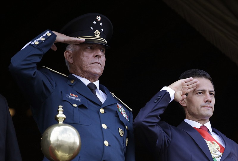 In this Sept. 16, 2016 file photo, Defense Secretary Gen. Salvador Cienfuegos, left, and Mexico's President Enrique Pena Nieto, salute during the annual Independence Day military parade in Mexico City's main square. Mexico's top diplomat says the country's former defense secretary, Gen. Salvador Cienfuegos, has been arrested in Los Angeles. Foreign Relations Secretary Marcelo Ebrard wrote Thursday, Oct. 15, 2020 in his Twitter account that U.S. Ambassador Christopher Landau had informed him of Cienfuegos' arrest. (AP Photo/Rebecca Blackwell, File)