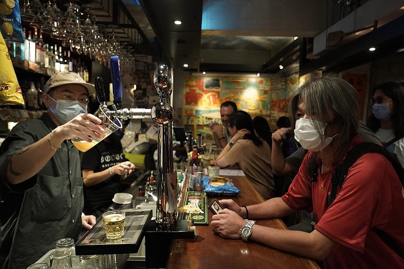 In this Oct. 9, 2020 photo, former lawmaker and pro-democracy activist Leung Kwok-hung, known as "Long Hair," right, waits for his drink at Club 71 in Hong Kong. The bar known as a gathering place for pro-democracy activists and intellectuals is closing. For years, the storied bar has served as a watering hole for the city's pro-democracy activists and intellectuals, who could freely engage in discussions over a round of beer or two. (AP Photo/Kin Cheung)