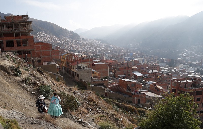 Women walk along a path before the opening of the polling stations for general elections in El Alto, Bolivia, Sunday, Oct. 18, 2020. (AP Photo/Juan Karita)