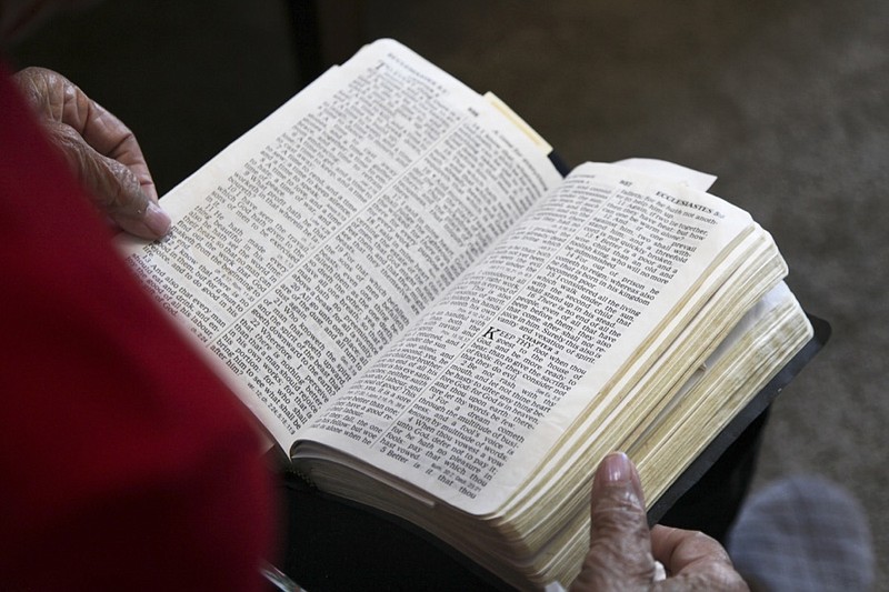 Hannah Carson reads from the third chapter of Ecclesiastes inside her Charlotte, N.C., apartment on Friday, Oct. 16, 2020. At 90-year-old, Carson reads her Bible daily, particularly her favorite verse detailing the different seasons of life. As soon as she received her absentee ballot in the mail six weeks ago, she filled it out and sent it back to her local election office. (AP Photo/Sarah Blake Morgan)