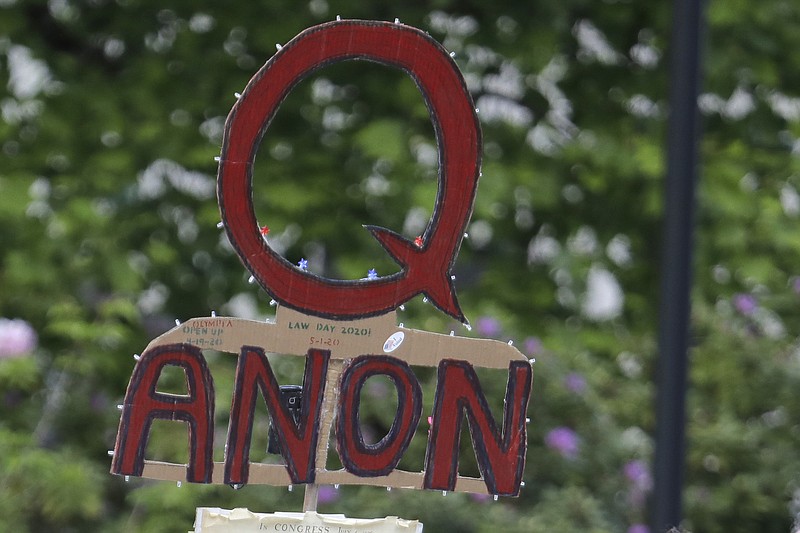 Photo by Ted S. Warren of The Associated Press / In this May 14, 2020, file photo, a person carries a sign supporting QAnon at a protest rally in Olympia, Washingotn.