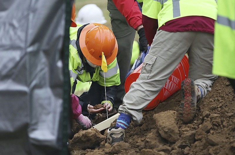 Researchers and work crews look at items pulled from the ground during a second test excavation and core sampling, Tuesday, Oct. 20, 2020, in the search for remains at Oaklawn Cemetery in Tulsa, Okla., from the 1921 Tulsa Race Massacre. (Mike Simons/Tulsa World via AP)


