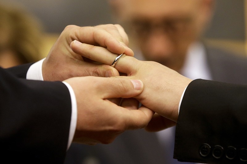 FILE - In this May 21, 2015 file photo, Mauro Cioffari, left, puts a wedding ring on his partner Davide Conti's finger as their civil union is being registered by a municipality officer during a ceremony in Rome's Campidoglio Capitol Hill. Pope Francis endorsed same-sex civil unions for the first time as pope while being interviewed for the feature-length documentary "Francesco," which premiered Wednesday, Oct. 21 2020 at the Rome Film Festival. (AP Photo/Gregorio Borgia, file)