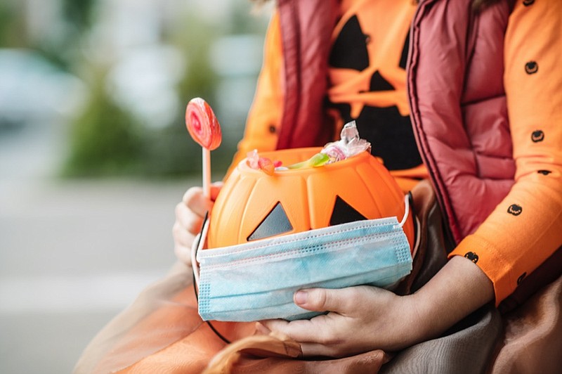 Child's basket with sweets and protective face mask on Halloween in autumn - stock photo halloween tile candy tile / Getty Images
