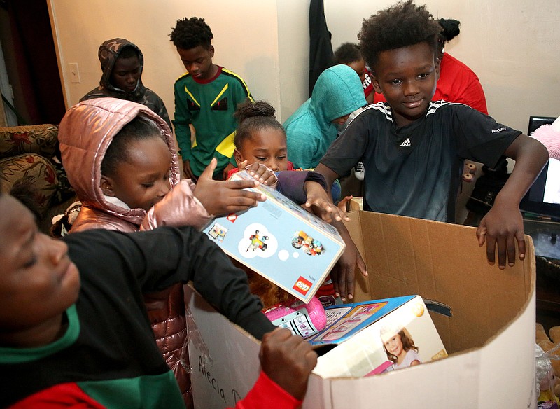 Staff photo by Erin O. Smith / From left, Ta'leq Robinson, 10, Samari Robinson, 7, Kamoira Ross, 5, and Tay'shawn Robinson, 9, dig through a box of toys delivered to their house by the Forgotten Child Fund's Santa Train on Dec. 24, 2019, in Chattanooga.