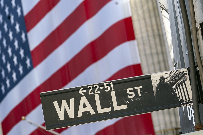 FILE - In this Monday, Sept. 21, 2020, file photo, a Wall Street street sign is framed by a giant American flag hanging on the New York Stock Exchange in New York. Stocks are falling in early trading on Wall Street Monday, Oct. 26, 2020, and deepening last week's losses. (AP Photo/Mary Altaffer, File)