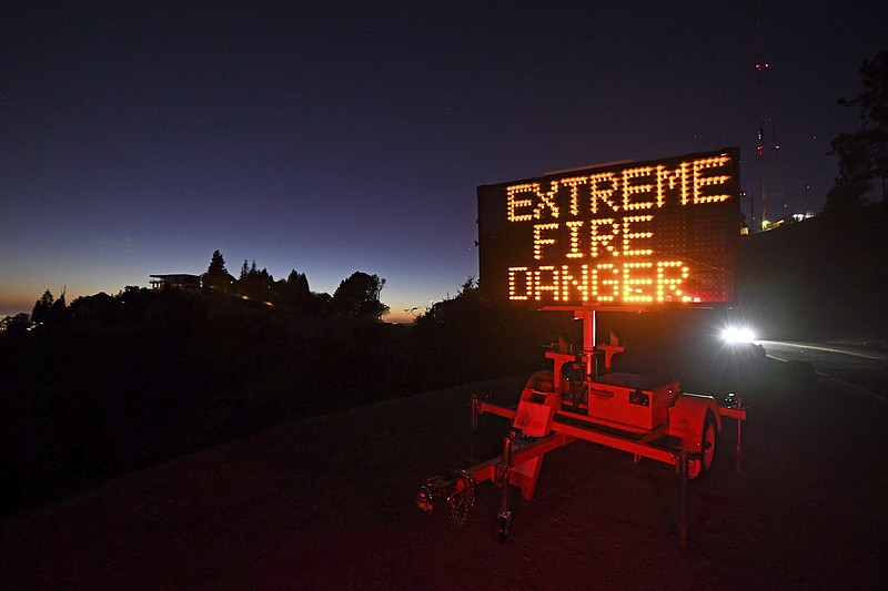 A roadside sign warns motorists of extreme fire danger on Grizzly Peak Boulevard, in Oakland, Calif., Sunday, Oct. 25, 2020. Due to high winds and dry conditions PG&E will turn off the power to over 361,000 customers in 36 counties to protect them from possible wildfires caused by downed power lines. The National Weather Service predicts offshore winds from the north peaking at higher elevations up to 70 mph. (Jose Carlos Fajardo/Bay Area News Group via AP)