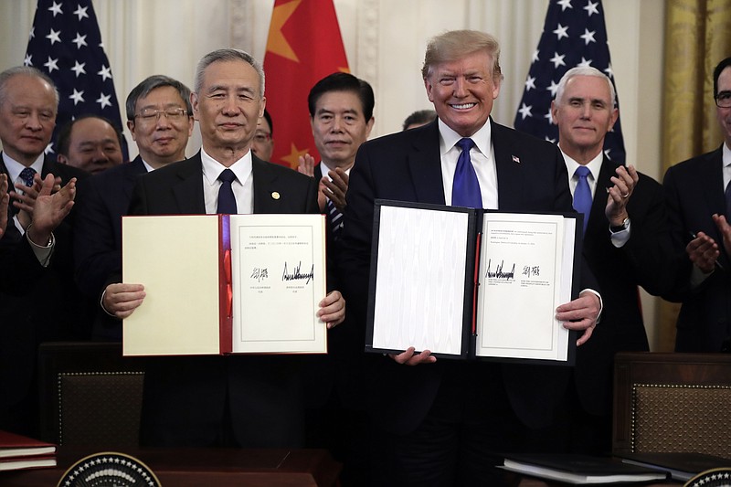 FILE - In this Jan. 15, 2020, file photo President Donald Trump holds a trade agreement with Chinese Vice Premier Liu He, in the East Room of the White House in Washington. Trump spent four years upending seven decades of American trade policy. He started a trade war with China, slammed America's closest allies by taxing their steel and aluminum and terrified Big Business by threatening to take a wrecking ball to $1.4 trillion in annual trade with Mexico and Canada. Trump's legacy on trade is likely to linger, regardless whether Joe Biden replaces him in the White House in January 2021.(AP Photo/Evan Vucci)