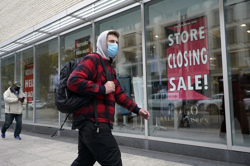 A passer-by walks past a store closing sign, right, in the window of a department store, Tuesday, Oct. 27, 2020, in Boston. (AP Photo/Steven Senne)


