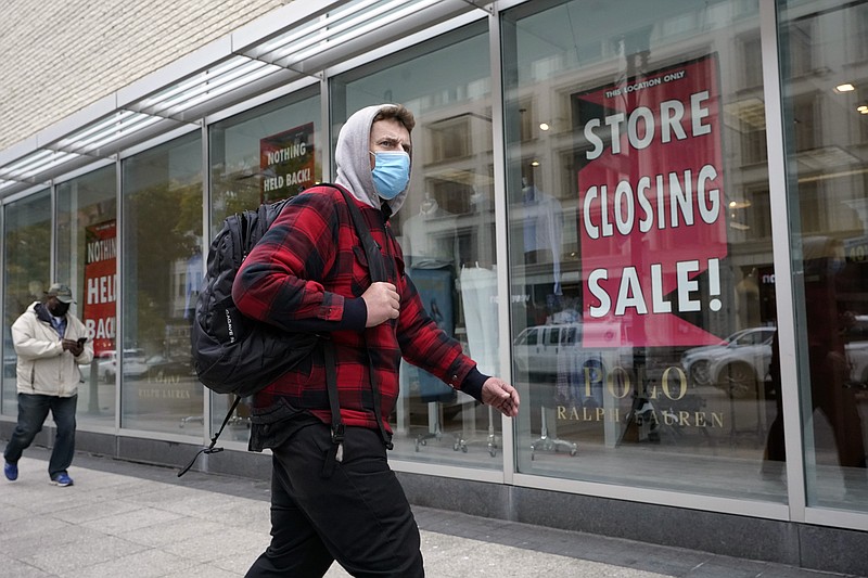 A passer-by walks past a store closing sign, right, in the window of a department store, Tuesday, Oct. 27, 2020, in Boston. Americans may feel whiplashed by a report Thursday, Oct. 29, on the economy's growth this summer, when an explosive rebound followed an epic collapse. The government will likely estimate that the economy grew faster on an annualized basis last quarter than in any such period since record-keeping began in 1947.(AP Photo/Steven Senne)